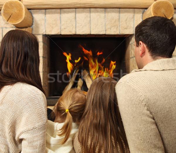 Young happy mother, father and two daughters by a fireplace Stock photo © dashapetrenko