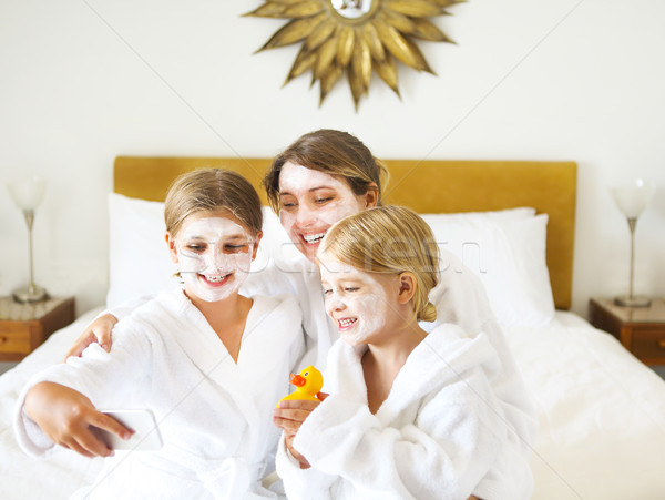 Happy mother and girls in bathrobes on bed Stock photo © dashapetrenko