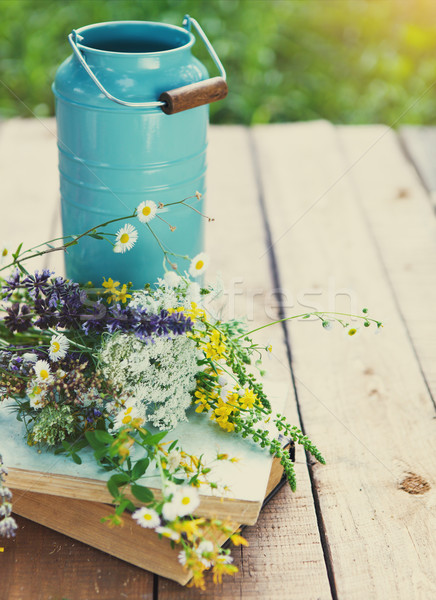 Flowers near watering can with old books on a rustic wooden tabl Stock photo © dashapetrenko