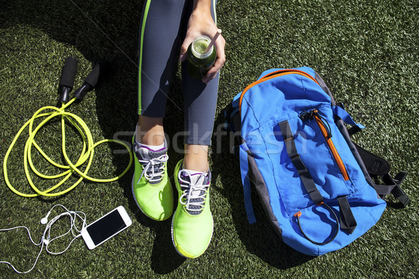Stock photo: Sporty woman holding green juice sitting on grass