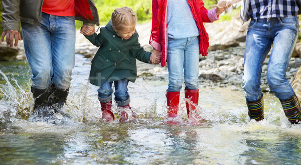 Happy family wearing rain boots jumping into a mountain river Stock photo © dashapetrenko