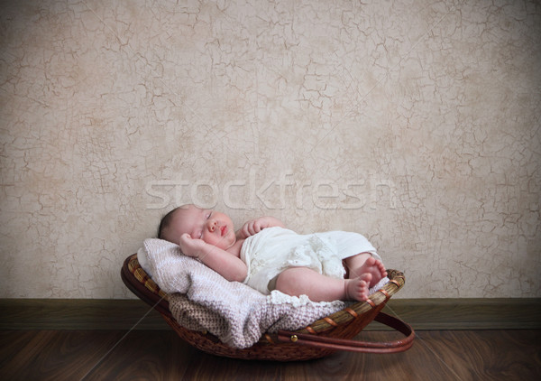 Baby Sleeping In The Basket On The Wooden Floor Stock Photo
