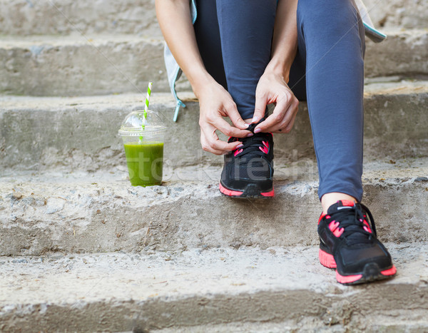 Green detox smoothie cup and woman lacing running shoes before w Stock photo © dashapetrenko