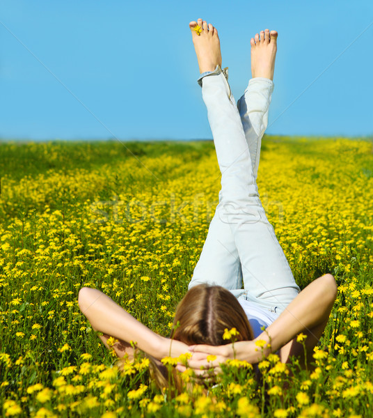 Stock photo: Young beautiful blond girl laying on the daisy flowers field