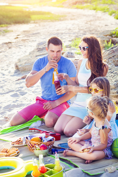 Family sitting on the sand at the beach at the summer picnic Stock photo © dashapetrenko