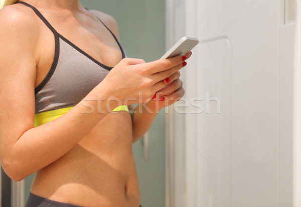 Szőke sportos nő szekrényes öltöző edzés mobiltelefon Stock fotó © dashapetrenko