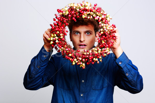 Funny man looking through a wreath over gray background Stock photo © deandrobot