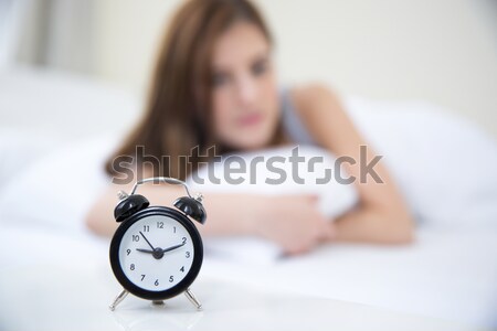 Woman waking up in the morning and looking on alarm clock. Focus on clock Stock photo © deandrobot