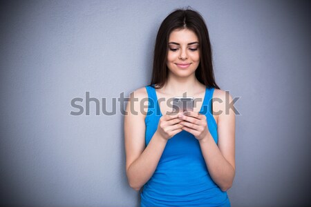 Femeie zambitoare smartphone gri albastru tricou Imagine de stoc © deandrobot
