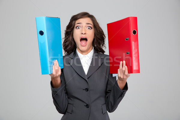 Crazy hysterical young woman screaming and holding colorful binders Stock photo © deandrobot