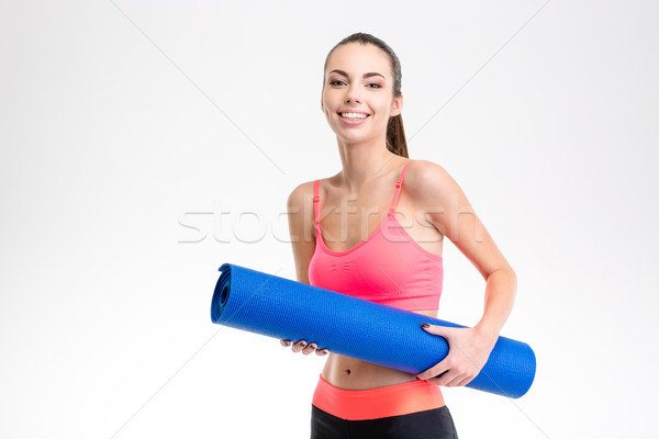 Portrait og smiling happy charming fitness girl with yoga mat Stock photo © deandrobot