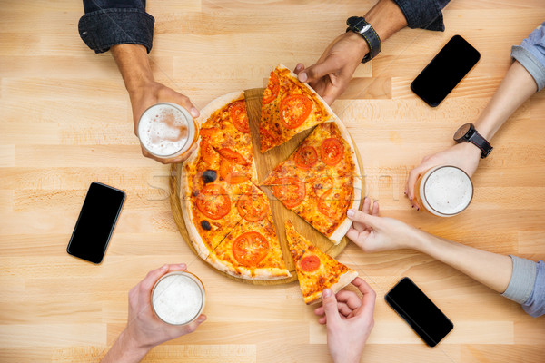 Amigos degustación pizza potable cerveza mesa de madera Foto stock © deandrobot