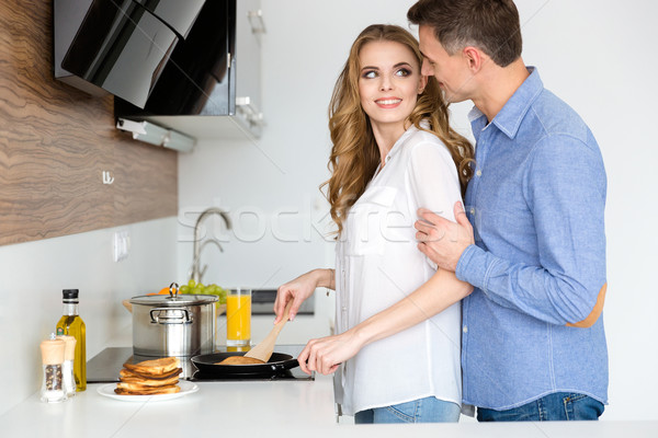 Beautiful wife making pancakes and flirting with husband  Stock photo © deandrobot
