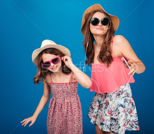 Two happy sisters listening to music with earphones and dancing Stock photo © deandrobot