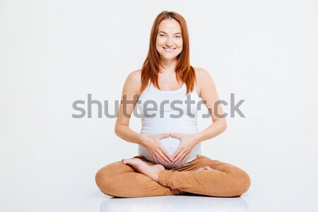 Pregnant woman showing heart gesture on her belly Stock photo © deandrobot