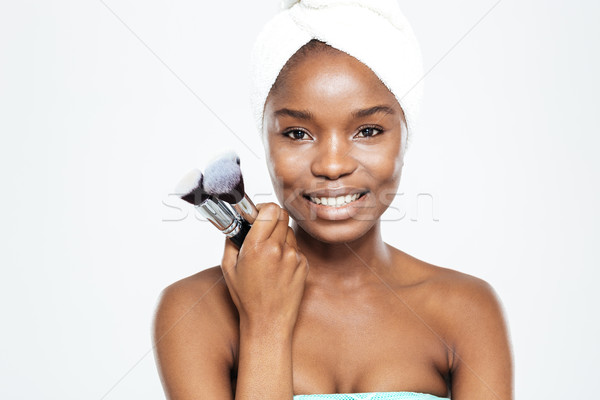 Smiling afro american woman holding makeup brushes Stock photo © deandrobot