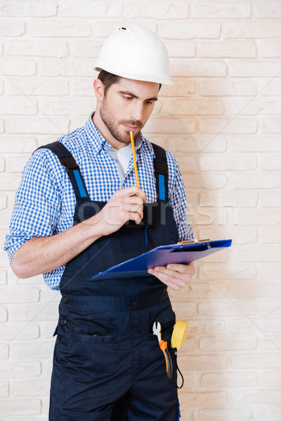 Construction worker thinking about something using clipboard Stock photo © deandrobot