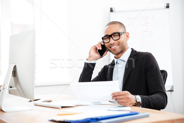 Happy smiling businessman holding documents and talking on mobile phone Stock photo © deandrobot