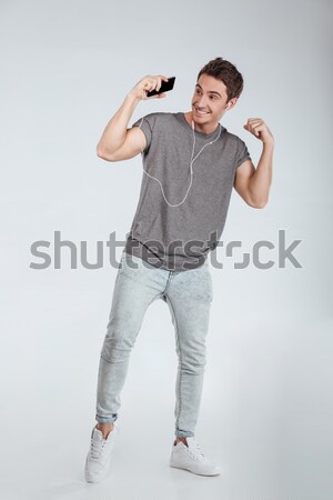 Young man in earphones dancing over white background Stock photo © deandrobot
