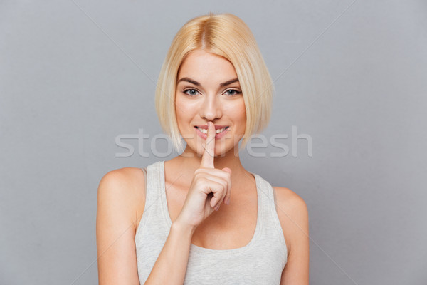 Potrait of smiling attractive young woman showing silence gesture Stock photo © deandrobot