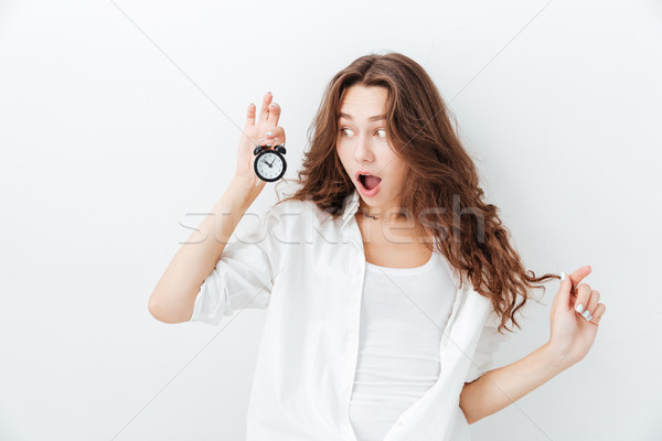 Cute amazed young girl looking at alarm clock Stock photo © deandrobot