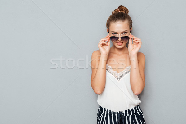 Confident young woman looking at camera through sunglasses Stock photo © deandrobot