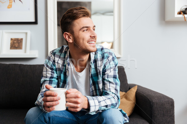 Happy young bristle man holding cup of tea. Stock photo © deandrobot