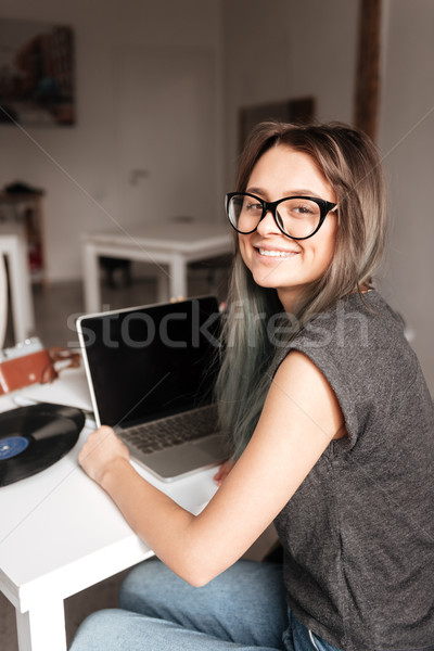 Smiling woman in glases sitting and using blank screen laptop Stock photo © deandrobot