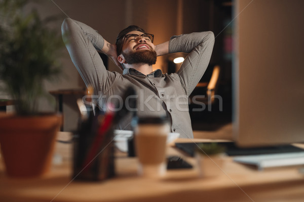 Cheerful bearded designer working stretching on the workplace Stock photo © deandrobot