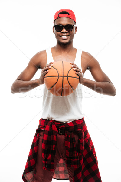 Cheerful african man in cap and sunglasses holding basketball ball Stock photo © deandrobot