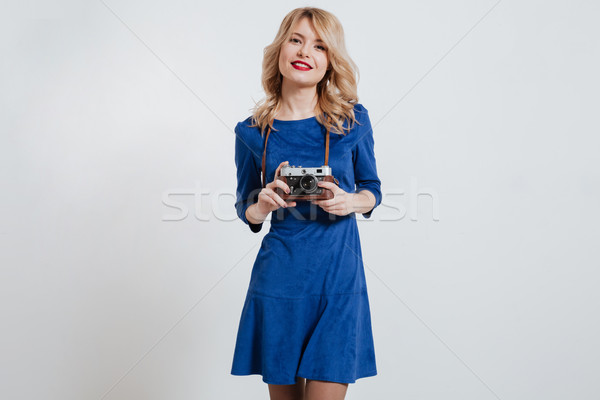 Pretty young lady holding camera over white background. Stock photo © deandrobot