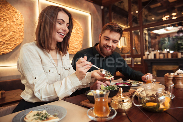 Young loving couple sitting in cafe and eating. Stock photo © deandrobot