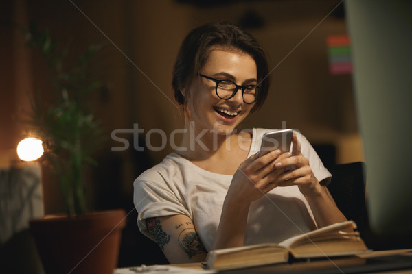 Happy lady designer sitting indoors at night chatting Stock photo © deandrobot