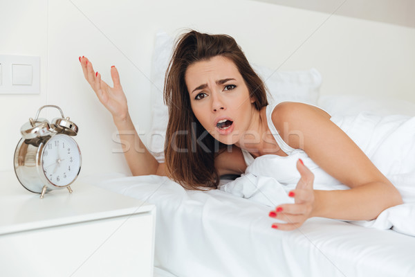 Frustrated confused woman laying in bed Stock photo © deandrobot