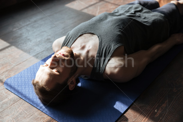 Concentrated young strong sportsman in gym lies on floor Stock photo © deandrobot