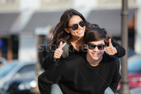 Young woman have fun outdoors with brother showing thumbs up. Stock photo © deandrobot