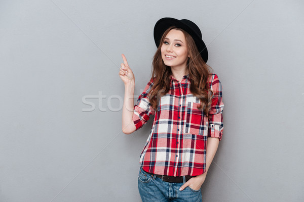 Cheerful girl in plaid shirt pointing finger up at copyspace Stock photo © deandrobot