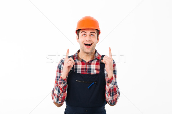 Portrait of a amused young male builder pointing two fingers Stock photo © deandrobot