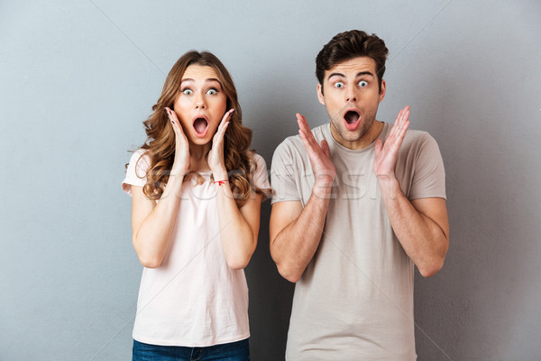 Happy excited couple standing with hands at their face Stock photo © deandrobot