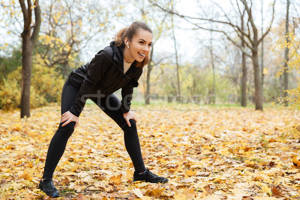 Stock photo: Portrait of a smiling fitness girl in earphones resting