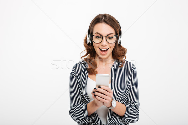 Happy beautiful young lady using mobile phone listening music Stock photo © deandrobot