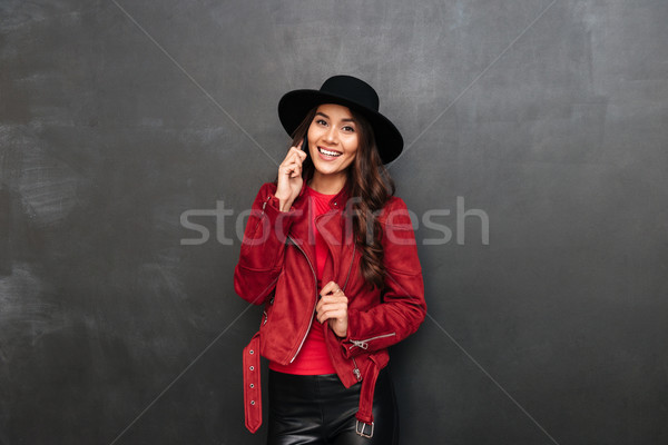 Cheerful young woman wearing hat talking by mobile phone Stock photo © deandrobot
