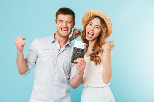 Happy caucasian loving couple holding passport with tickets make winer gesture. Stock photo © deandrobot