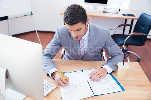Businessman signing document in office Stock photo © deandrobot