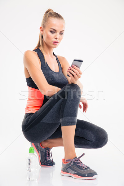 Sports woman sitting on the floor and using smartphone Stock photo © deandrobot