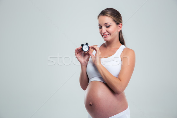 Happy pregnant woman holding alarm clock Stock photo © deandrobot