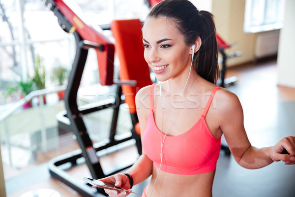 Vrolijk vrouw atleet luisteren naar muziek mobiele telefoon aantrekkelijk Stockfoto © deandrobot