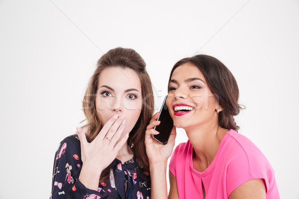Shocked woman overhearing conversation of cheerful female with mobile phone Stock photo © deandrobot