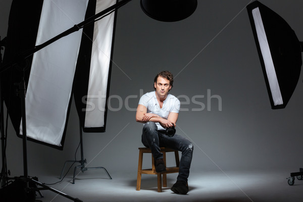 Male photograph sitting on the chair in professinal studio Stock photo © deandrobot