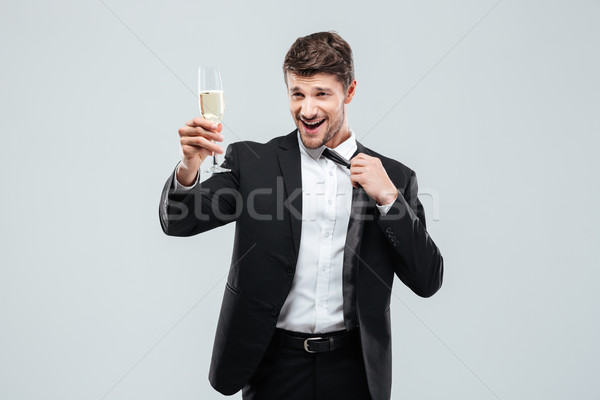 Happy businessman with glass of chamagne standing and making cheers Stock photo © deandrobot